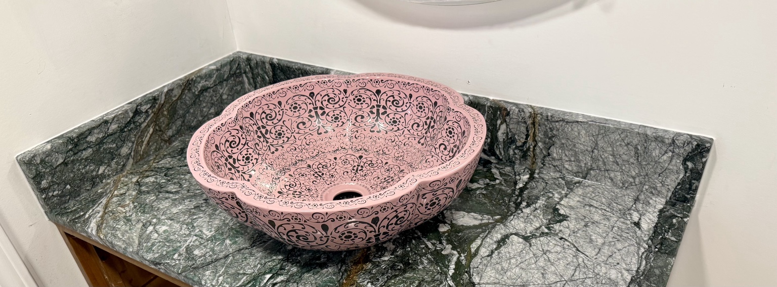 Dramatic green stone vanity with a decorative pink vessel sink