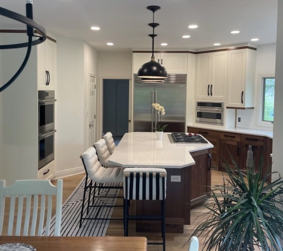 Finished kitchen with a black pendant light and seating at the stone island