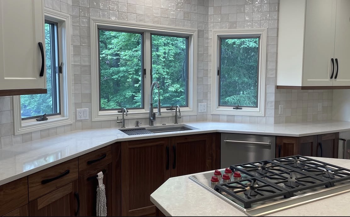 Bright finished kitchen with windows, a cooktop and white stone counters
